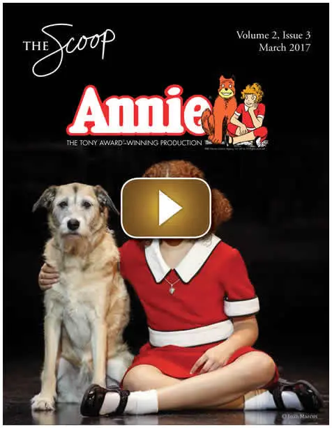 A girl in a red dress with a dog in a promotional image for Annie.