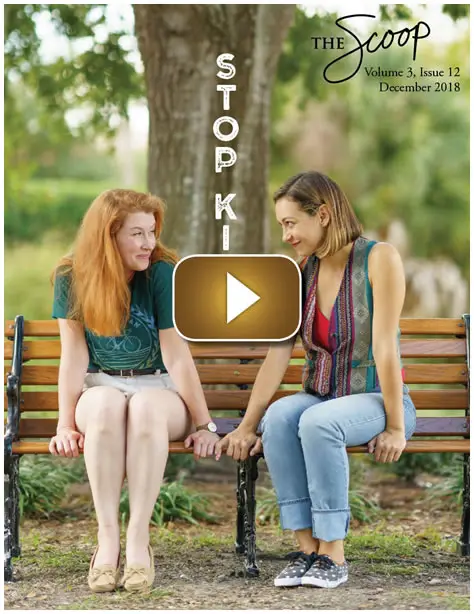 Two women talking on a park bench by a stop sign.