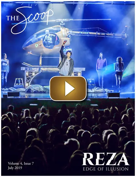 A singer performs live on stage with a helicopter backdrop and a large audience.