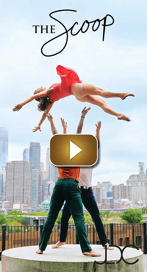 Two dancers performing an acrobatic lift against a city skyline.