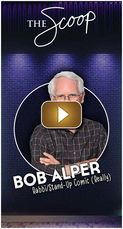 A man with white hair and glasses posing with arms crossed against a blue background.