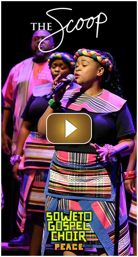 Woman singing in traditional colorful attire with others in the background.