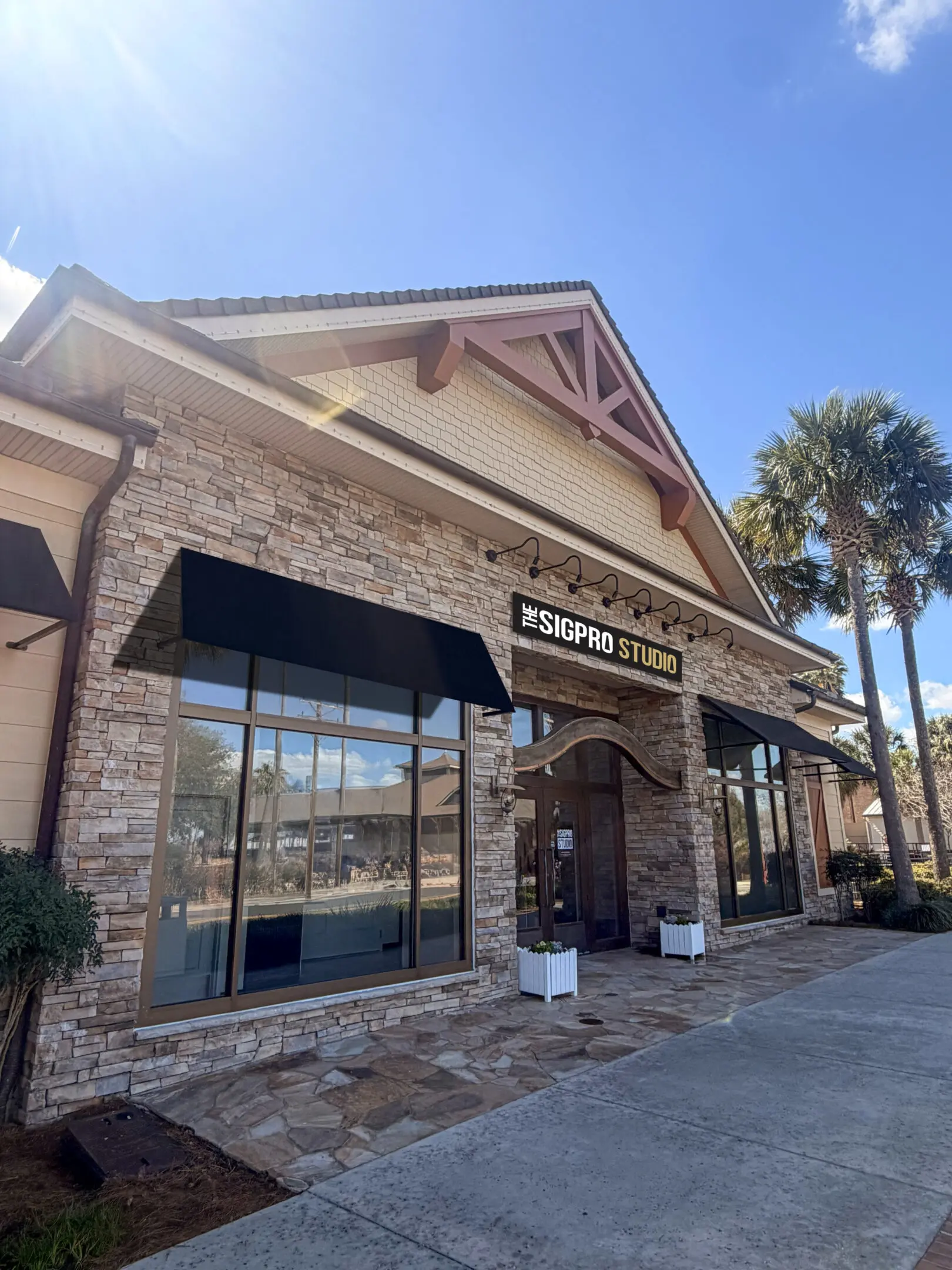 Exterior of a stone-clad restaurant with palm trees nearby.