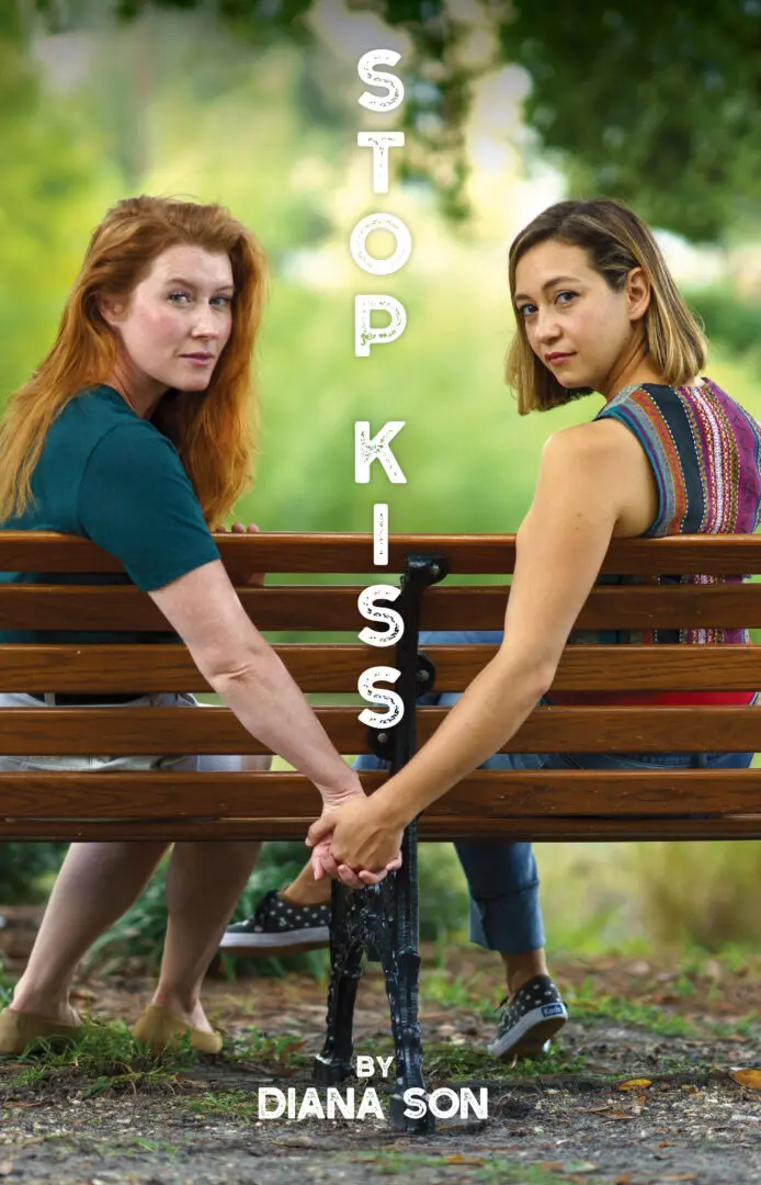 Two women holding hands on park bench