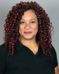 Smiling woman with curly maroon hair wearing a black top.